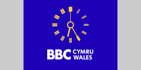 Yellow clock with white BBC CYMRU WALES lettering underneath, all on a blue background